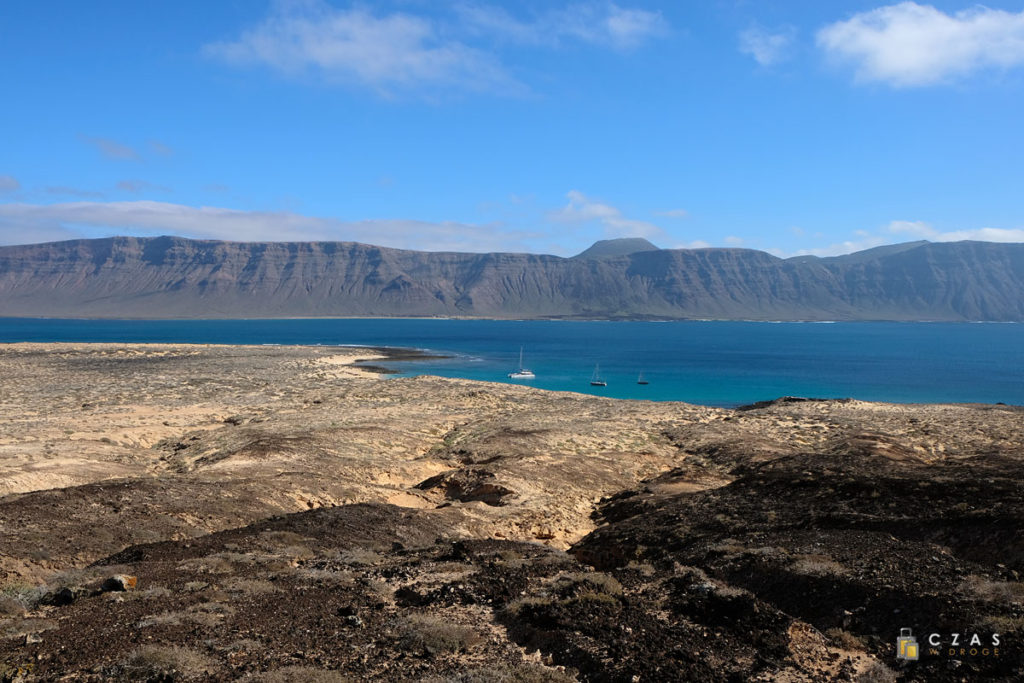 Piaszczysty krajobraz La Graciosy. W tle klify Lanzarote.